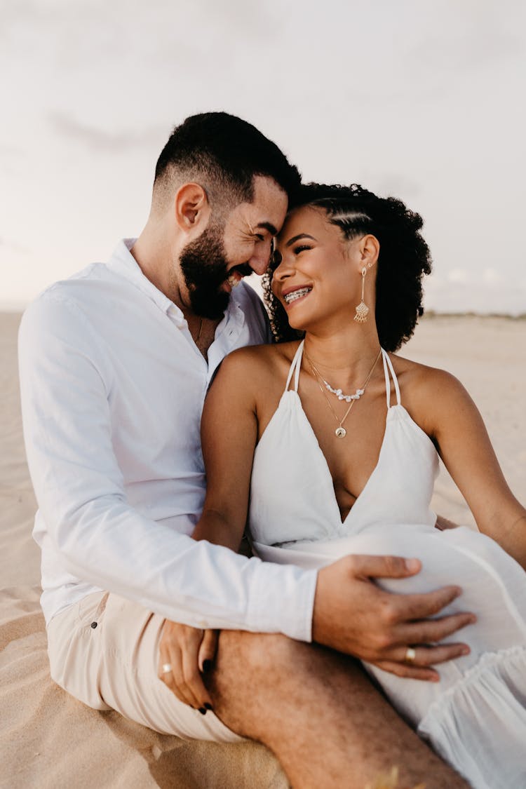 Man Sitting On Beach And Hugging Woman In His Arms