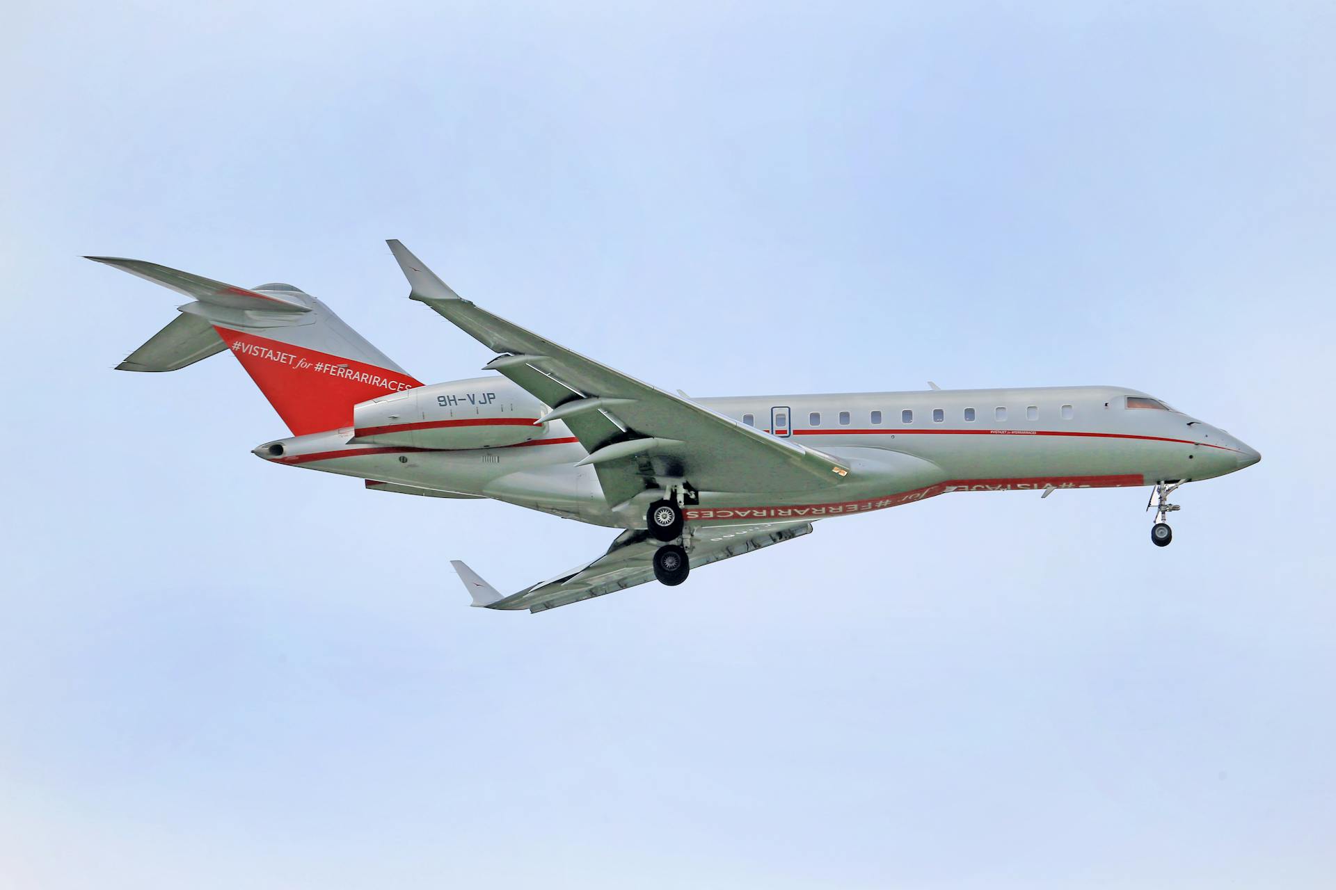 Elegant private jet in mid-air with landing gear down against a clear sky backdrop.