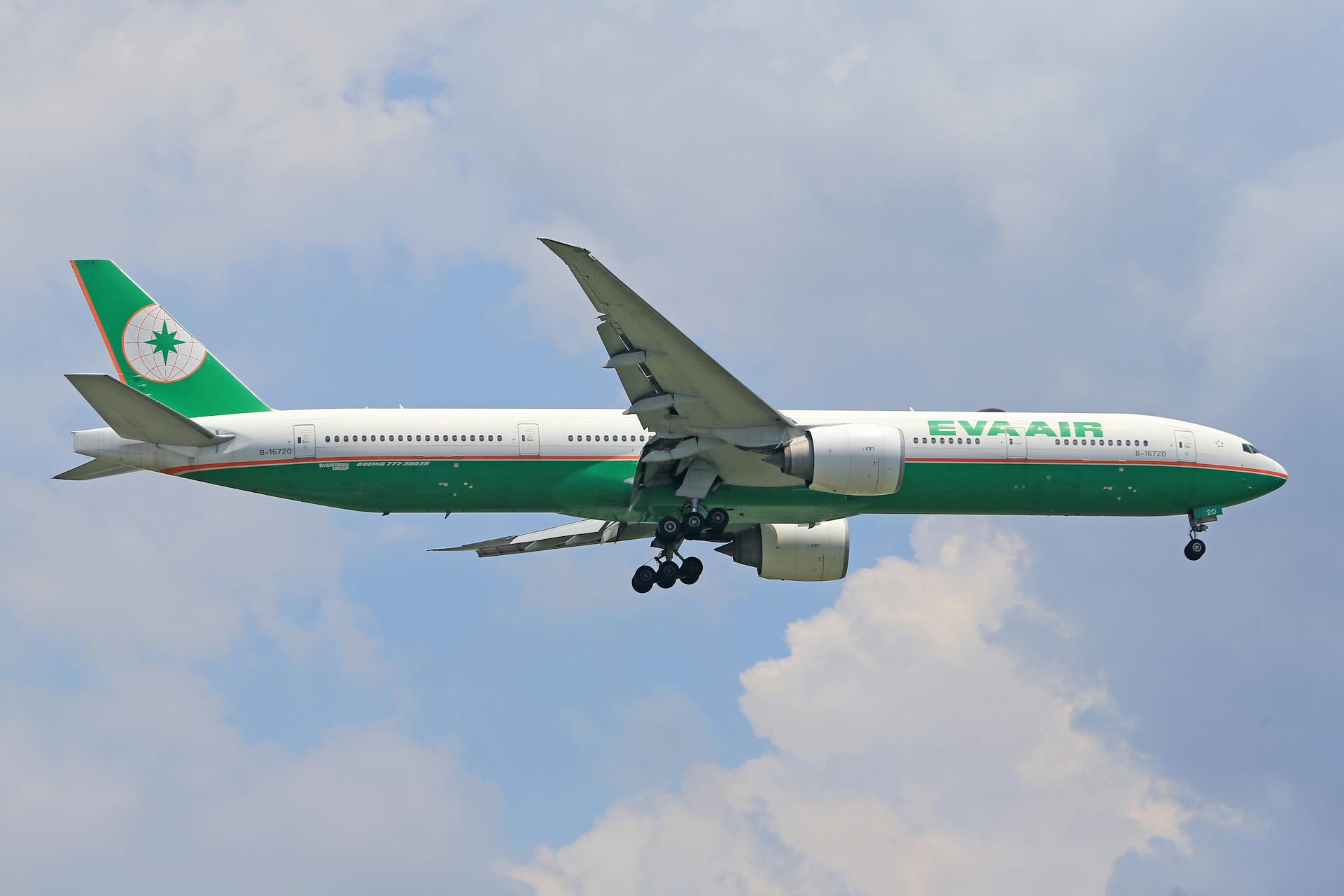 EVA Air passenger airplane in flight against a blue sky with clouds.