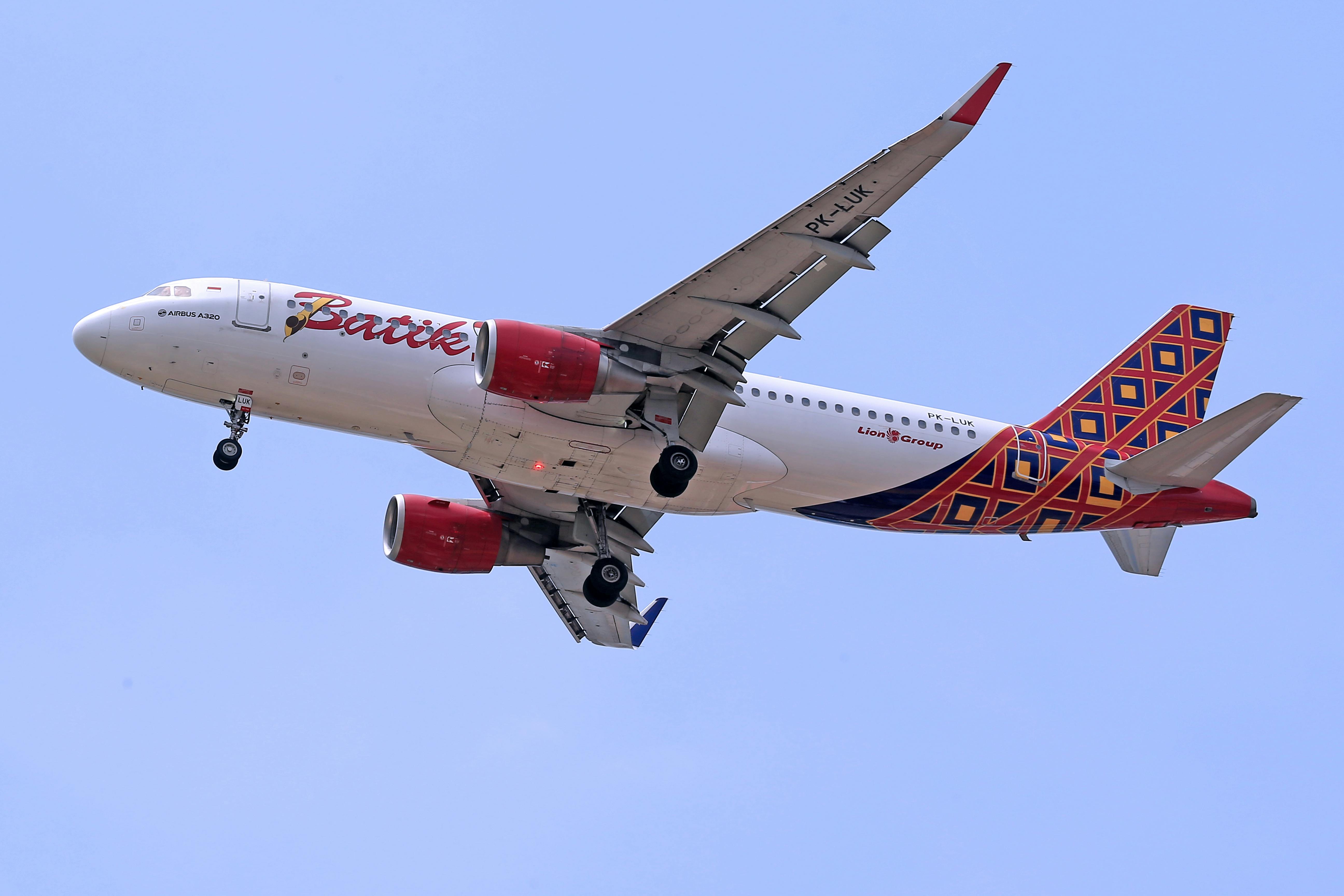 Batik Air Airbus A320 flying with unique tail design against clear blue sky.