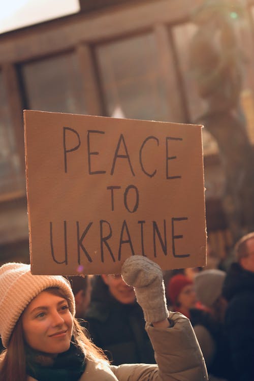 Free A Woman Wearing Winter Clothing Holding a Placard with Message Stock Photo