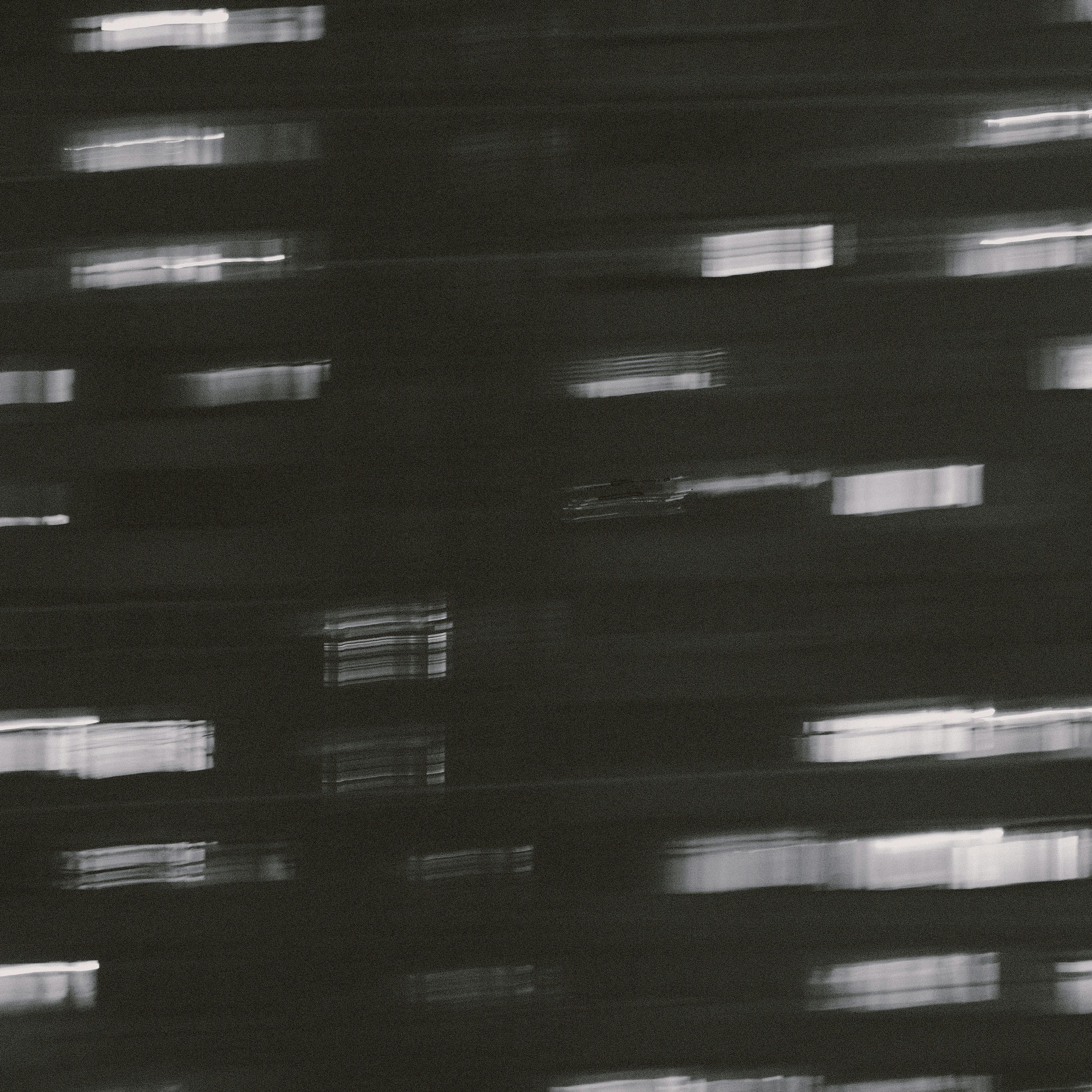 Blurred grayscale image capturing an abstract urban building at night.