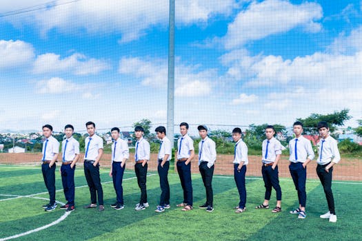 A group of young men in uniforms pose confidently on a soccer field under a clear blue sky.