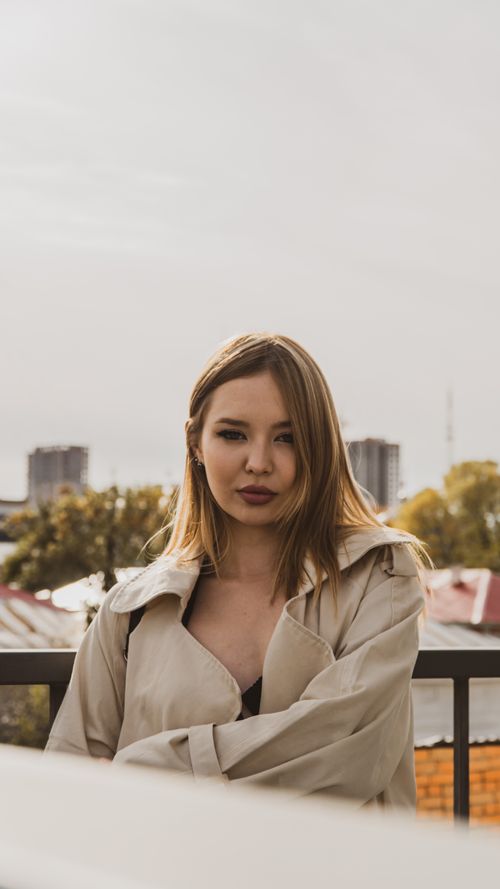 Free Trendy woman standing outdoors with cityscape background, exuding confidence. Stock Photo
