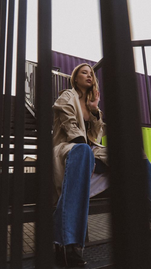 Free Fashionable woman in casual outfit sitting on colorful industrial stairs in an urban setting. Stock Photo