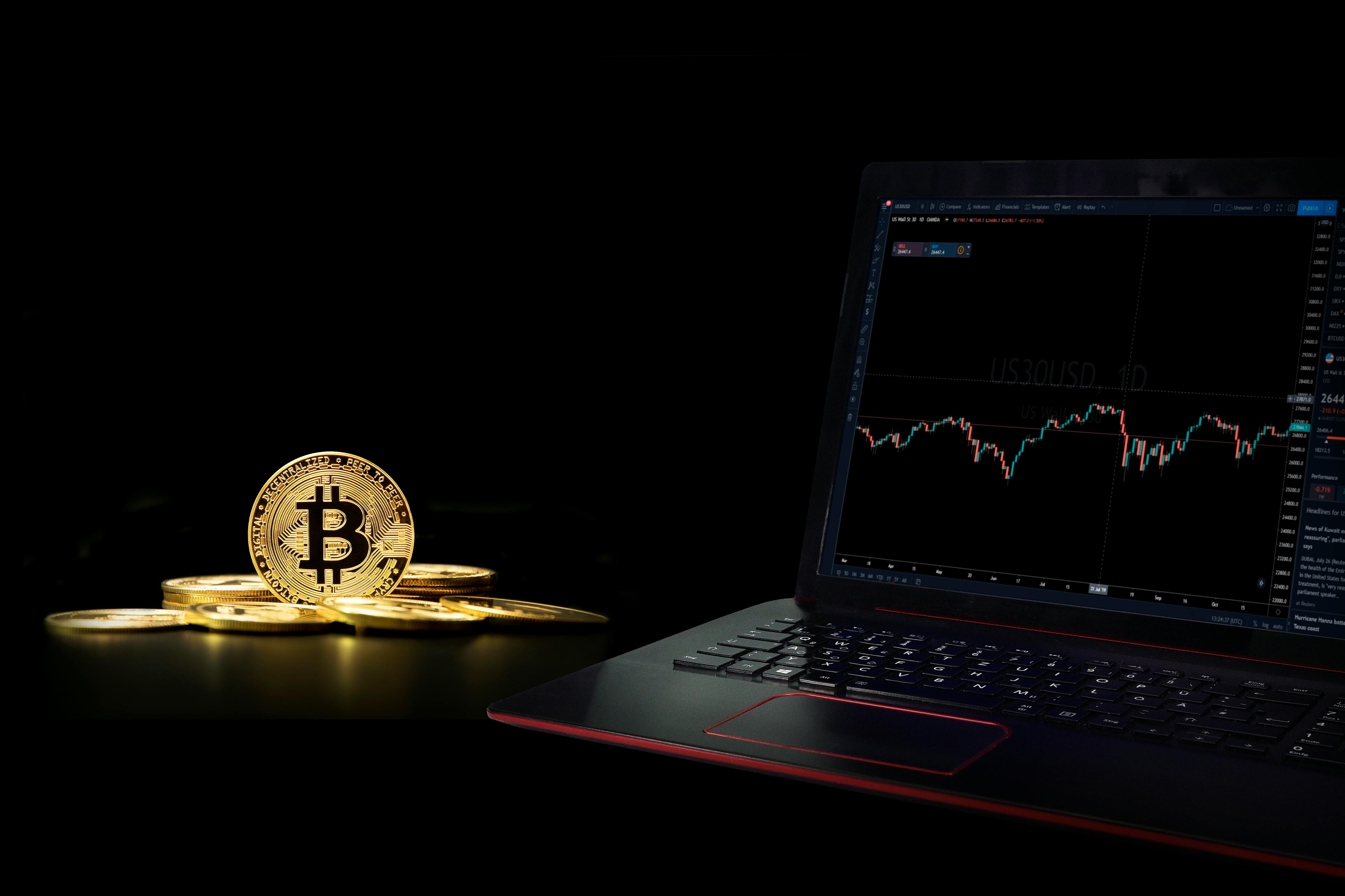 a laptop displaying a graph beside a commemorative coin