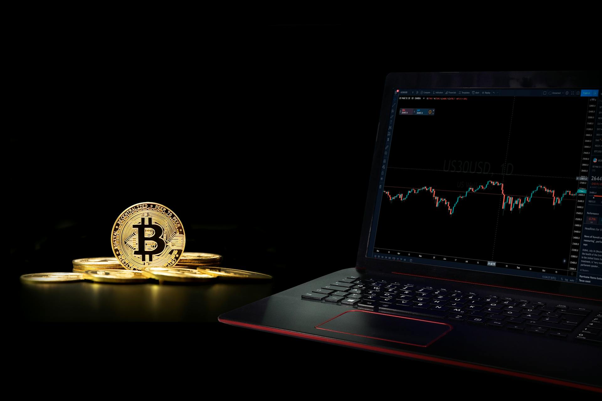 A Laptop Displaying a Graph beside a Commemorative Coin