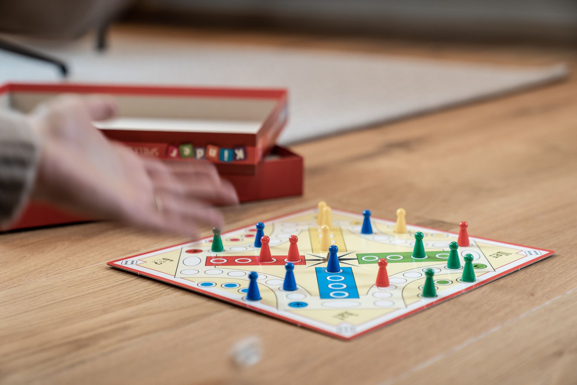 Close-up of a Ludo game with colorful pieces on a wooden floor with selective focus.
