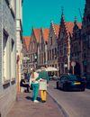 Woman in White Jacket and Green Pants Holding Umbrella Walking on Sidewalk