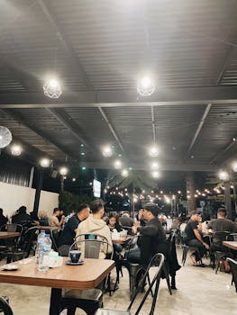 A contemporary restaurant filled with people enjoying meals under stylish lighting and decor.