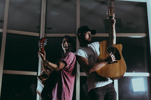 Free Two musicians joyfully playing acoustic guitars indoors at night. Stock Photo