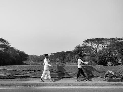 Grayscale Photo of Men Walking on Sidewalk