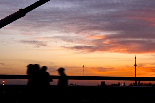Silhouetted people walking against a vibrant Johannesburg sunset backdrop with cloudy sky.