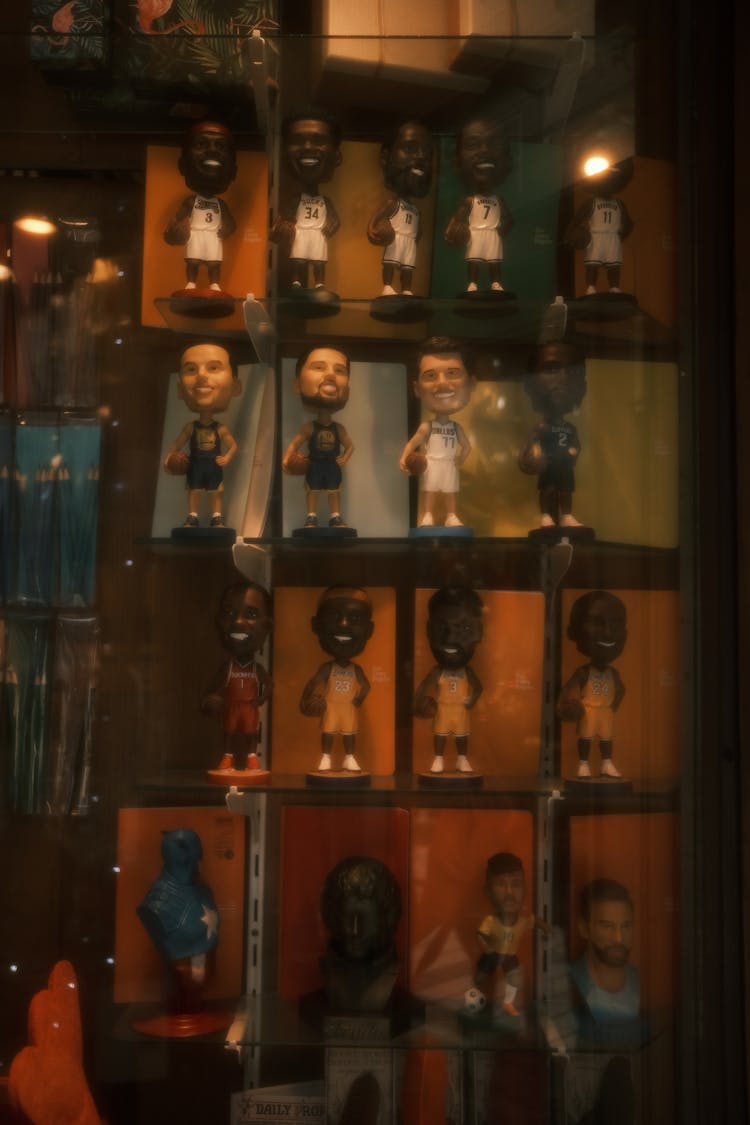 
A Collection Of Bobblehead Figurines In A Shelf