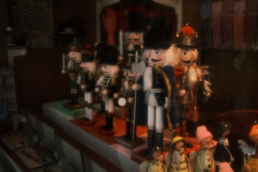 A collection of nutcracker figurines brightly displayed in a store window, evoking holiday charm.