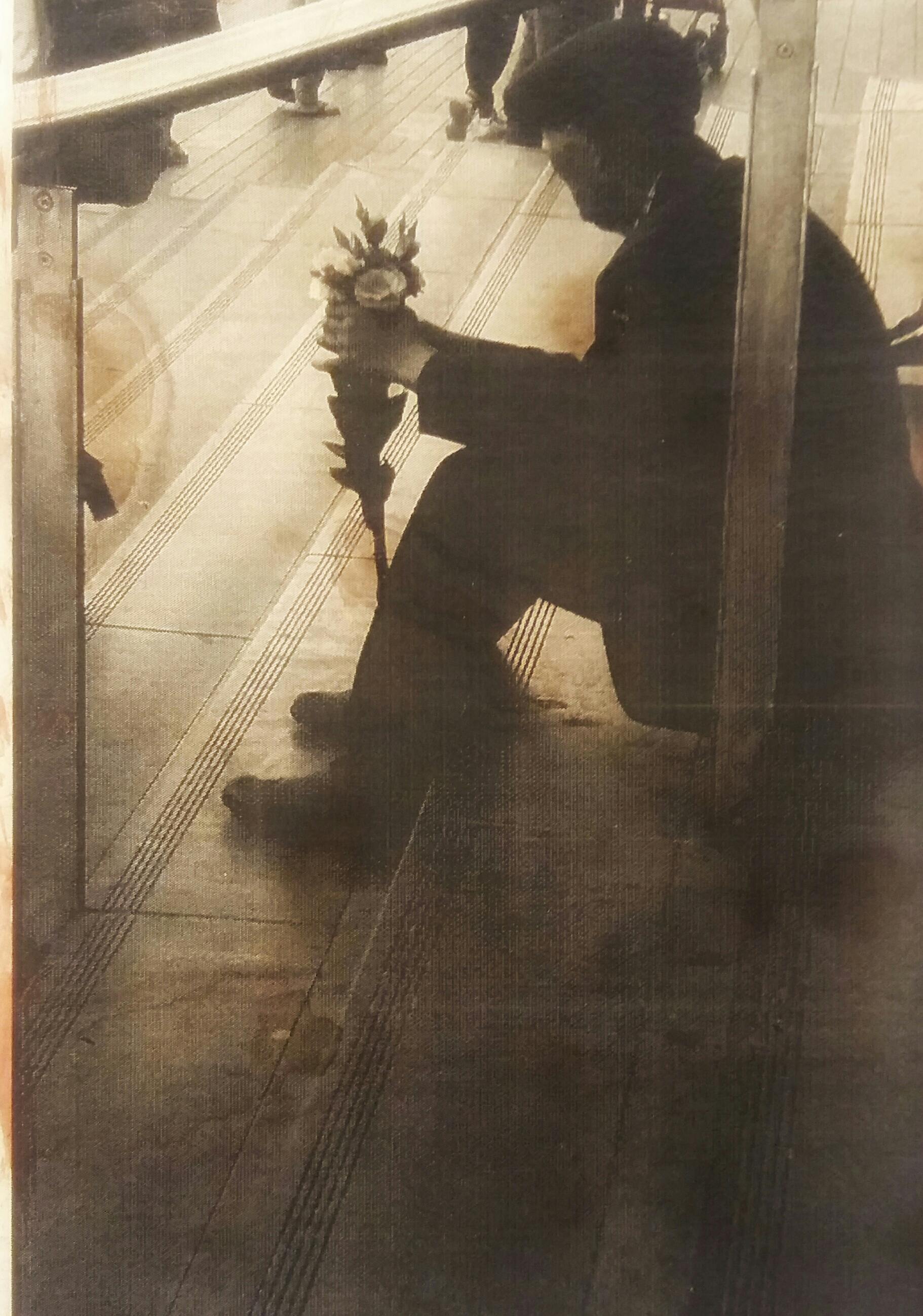 Sepia-toned image of a man holding a bouquet while sitting on stairs.
