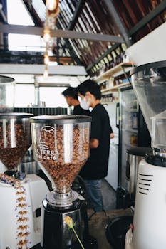 Baristas working in a cozy café with coffee grinders and beans displayed prominently.