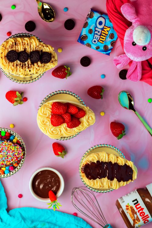 Free A vibrant flat lay of various desserts with sprinkles, strawberries, and a pink stuffed toy on a pink background. Stock Photo