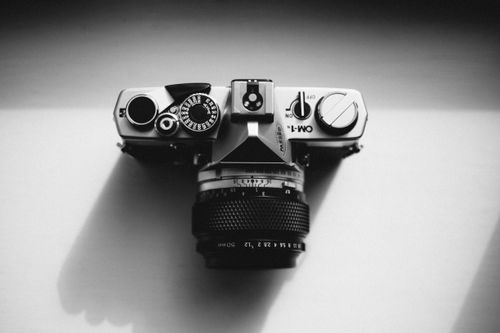 Free Top view of a vintage analog camera showcasing classic photography equipment in elegant black and white. Stock Photo