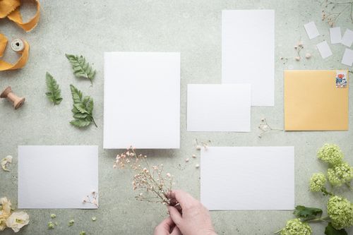 Free Elegant flat lay composition of blank papers, greenery, and flowers on a gray background. Stock Photo
