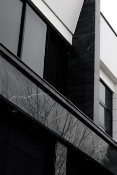 Elegant modern facade with black marble tiles and windows reflecting urban surroundings.