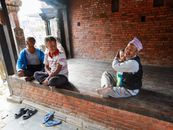 A joyful moment of family bonding with adults and a child on a traditional Nepalese brick porch.