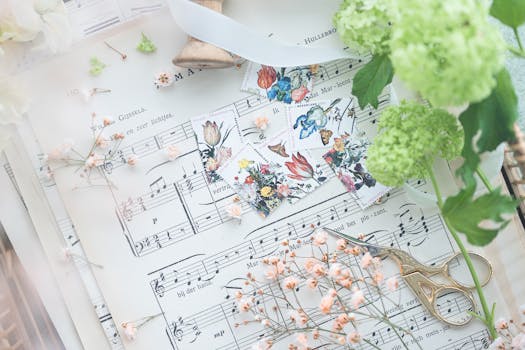 A delicate flat lay of flowers, vintage scissors, and sheet music, creating a romantic and artistic ambiance.