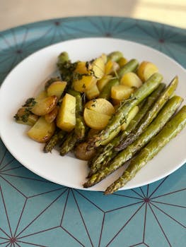 Delicious roasted potatoes and asparagus served on a white plate.