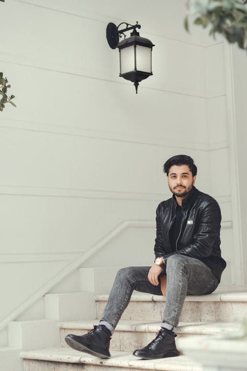 Free Man with a Beard in a Leather Jacket Sitting on a Staircase Stock Photo