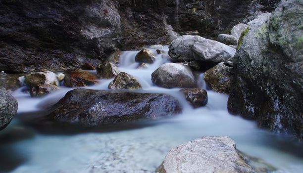 Long exposure of a serene stream cascading over smooth rocks in a natural setting.