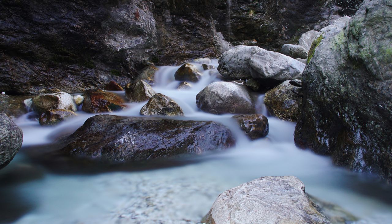 long exposure of a serene stream cascading over smooth rocks in a natu