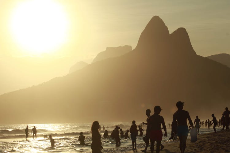 Sun Over Silhouettes Of People On Beach