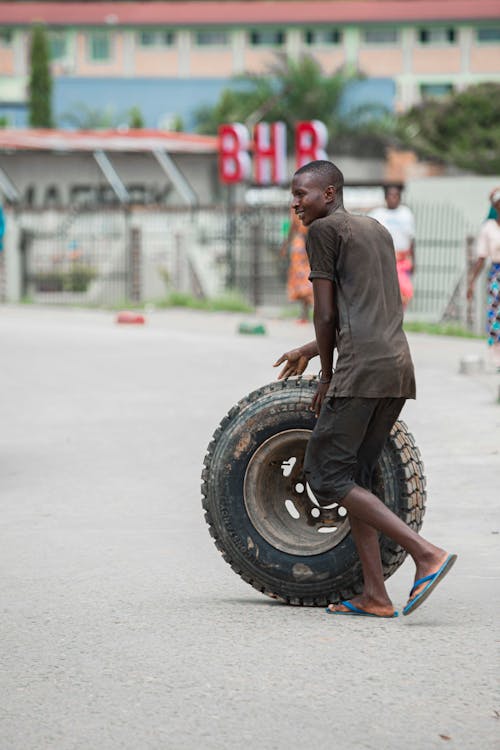 A Man Walking while Pushing a Tire