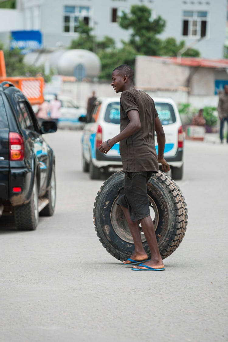 Man Walking With Tyre On Street