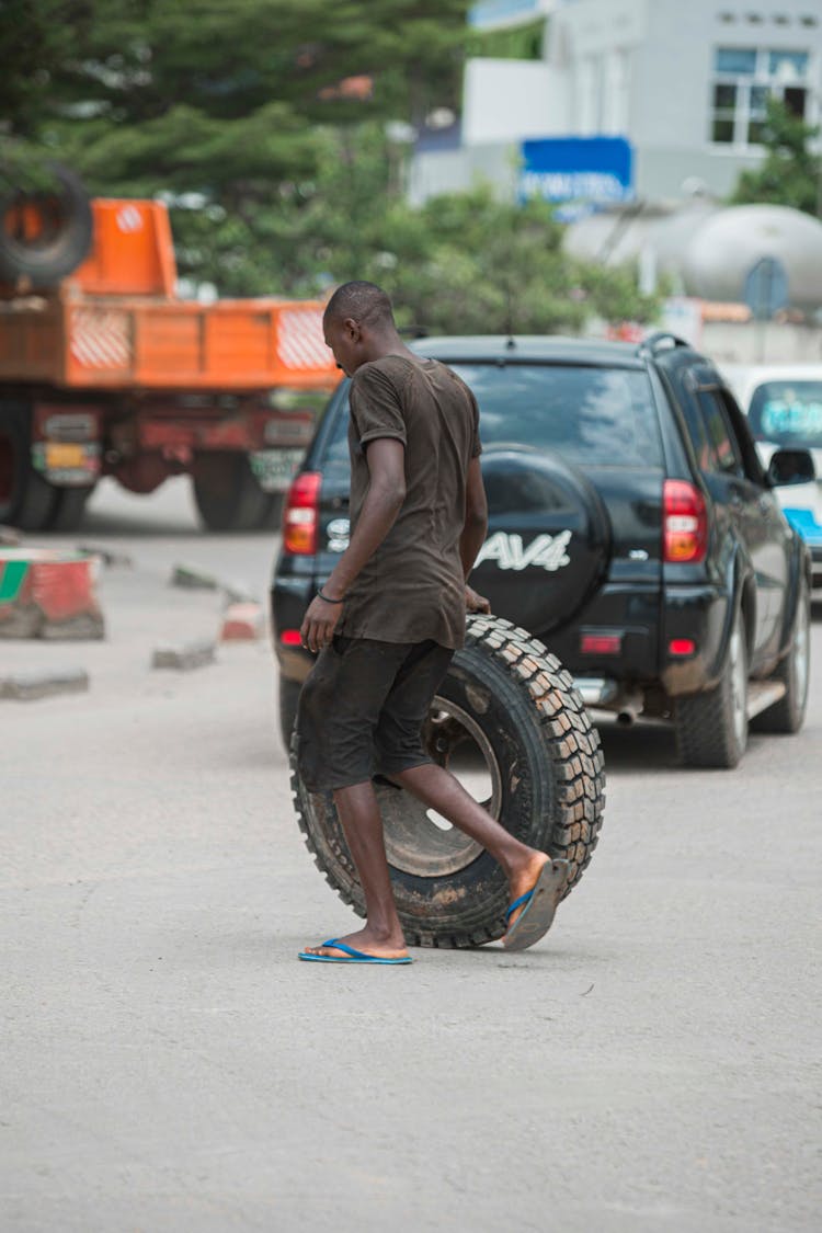 Man Crossing Street Carrying Tire