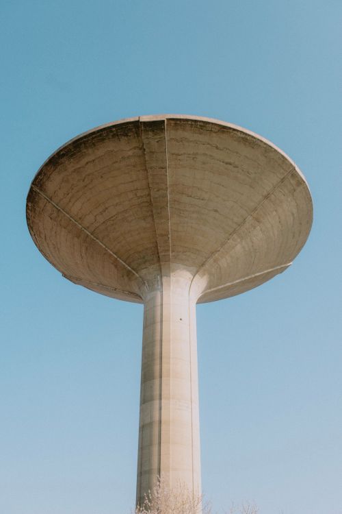 Free A minimalist low angle view of a concrete water tower with a clear blue sky background. Stock Photo