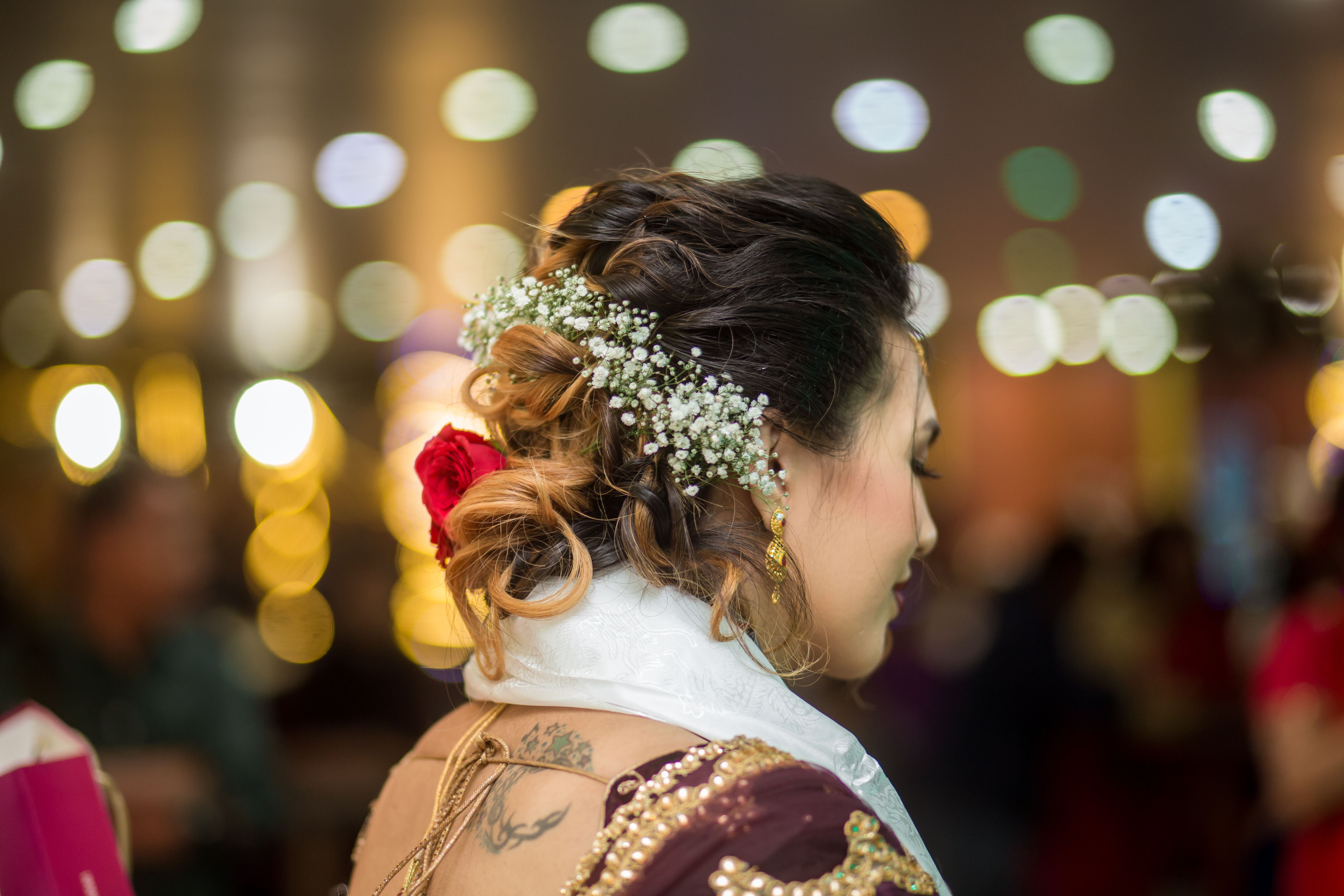 Close-up of a bridal hairstyle adorned with flowers and elegant jewelry at a festive event.