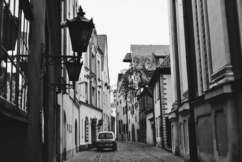 Free Black and white photo of a charming street in Old Town, Riga, featuring historical architecture and cobblestones. Stock Photo
