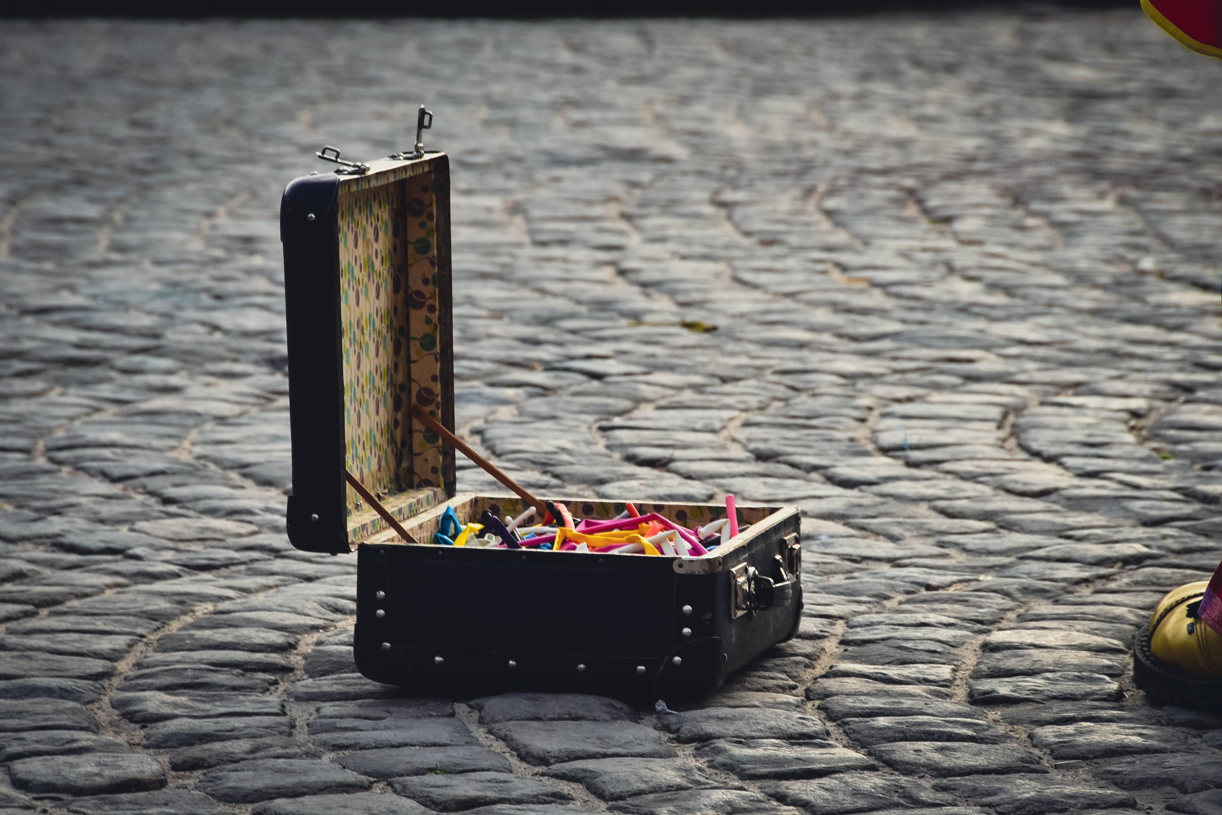 Colorful open suitcase filled with balloons on cobblestone street in Kazimierz Dolny, Poland.