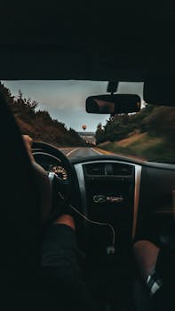 Interior car view on a scenic drive at sunset with a balloon on the horizon.