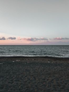Tranquil beach scene at sunset with soft clouds and gentle waves, ideal for relaxation themes.