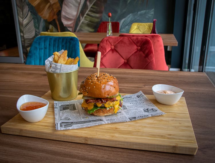 Cheeseburger And Chips On A Wooden Board In A Bar