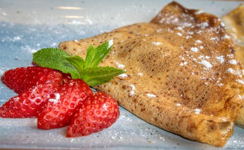 Free Close-up of a crepe dusted with sugar, garnished with ripe strawberries and fresh mint leaves. Stock Photo