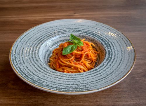 Free A plate of classic Italian spaghetti with tomato sauce and basil on a wooden table. Stock Photo