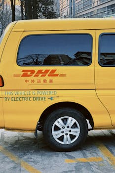 Yellow electric delivery van with DHL branding parked outdoors. Eco-friendly vehicle.