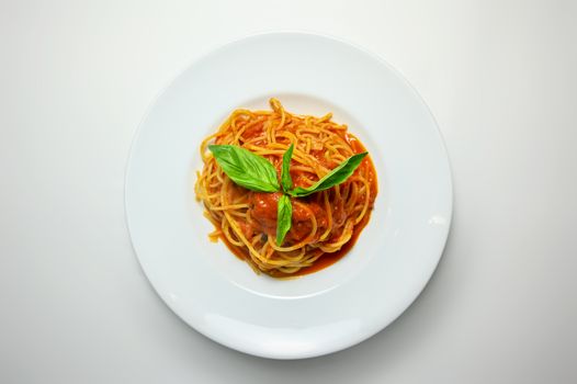 Plate of spaghetti topped with tomato sauce and fresh basil, showcasing classic Italian cuisine.