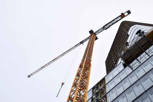 Low angle view of a skyscraper under construction with a tower crane against a sky.
