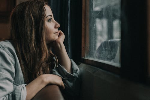 Free A Woman Looking outside a Window Stock Photo