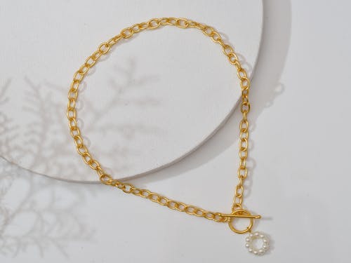 A Gold Necklace on White Surface