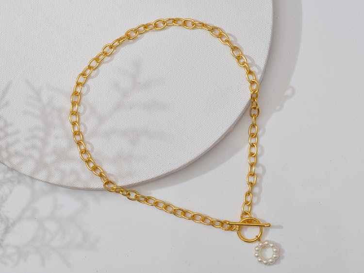 A Gold Necklace On White Surface